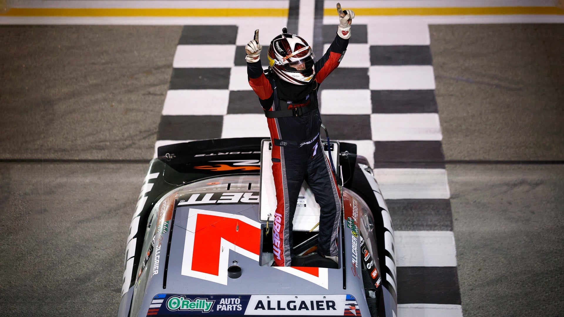Justin Allgaier stands on his car in a custom K1 RaceGear suit after winning Focused Health 250.