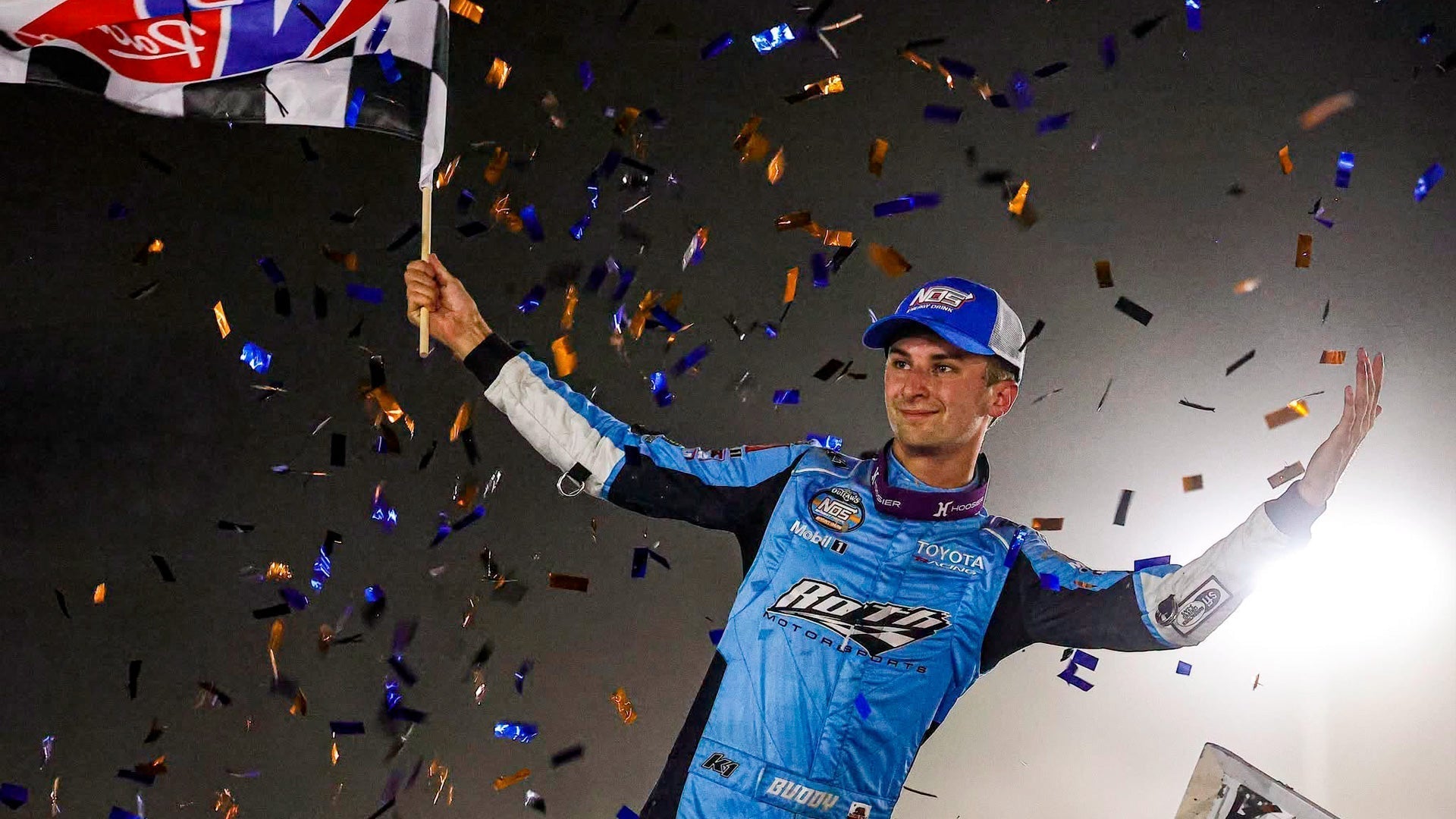 Buddy Kofoid waves the checker flag in his custom K1 RaceGear suit after winning at Wilmot Raceway
