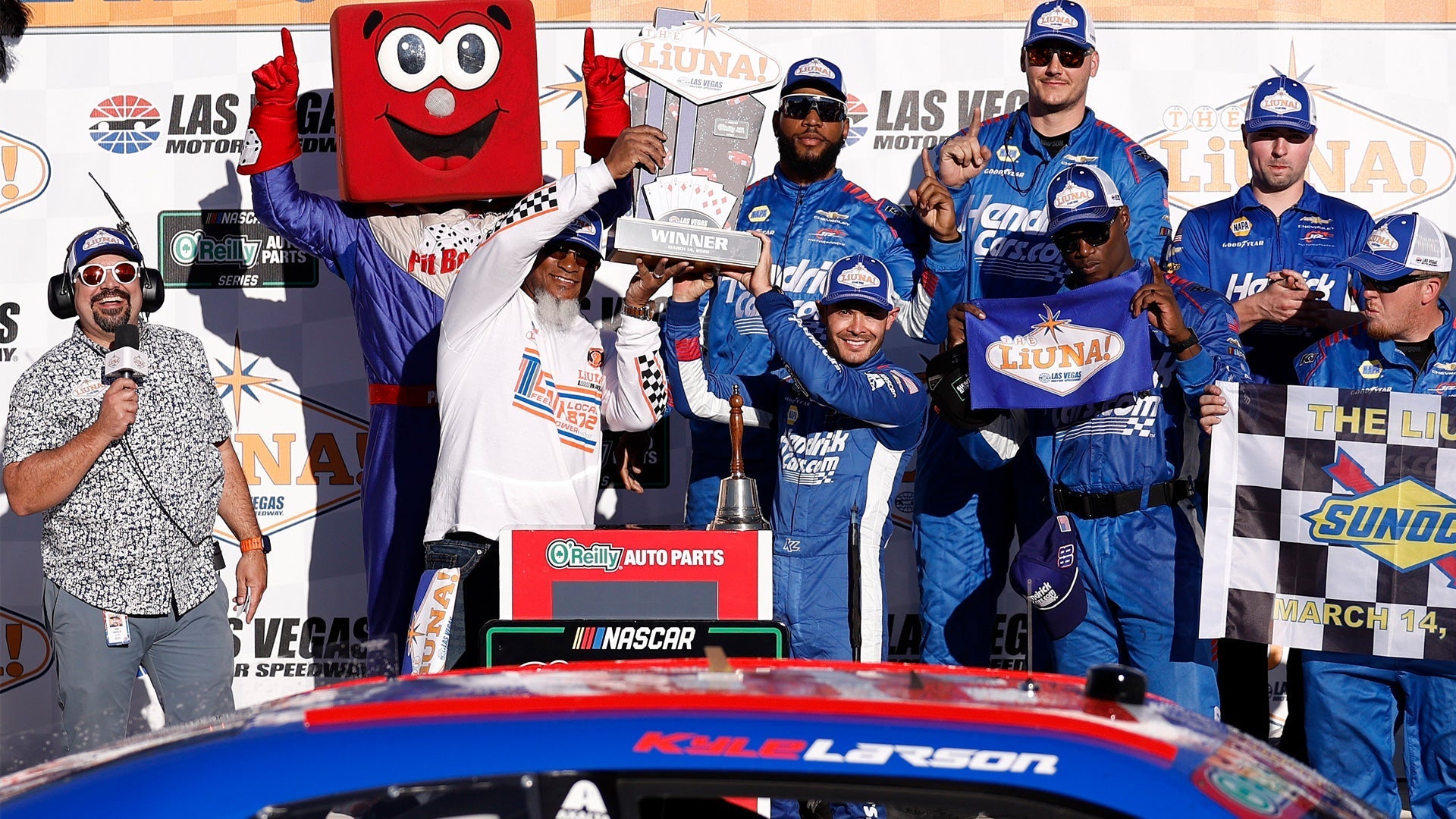 Kyle Larson and tem in K1 custom suits in victory circle.